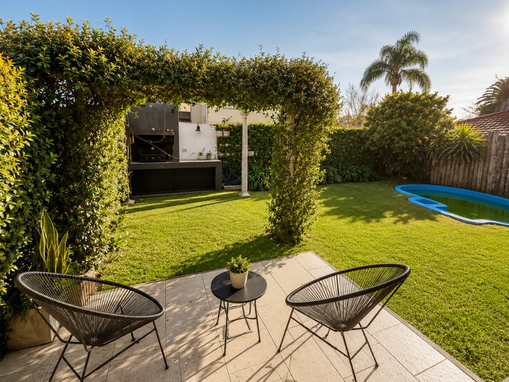 Jardín de la casa en Castelar con pérgola cubierta de enredadera, parrilla, césped y pileta